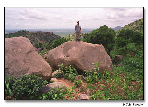 Alex on mountain rock overlooking Mora, Cameroon, Africa