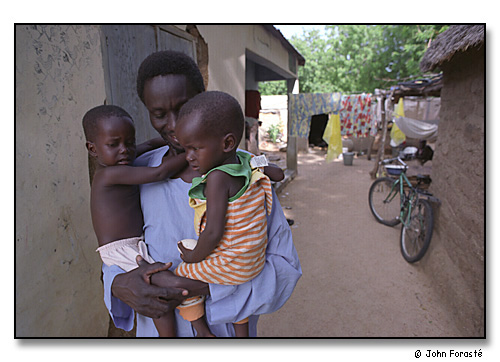 Mamadou Bimba Djouma with his twins, Dairou and Aissata, outside their house. <br>Mora, Cameroon, (central west) Africa. August 2002.